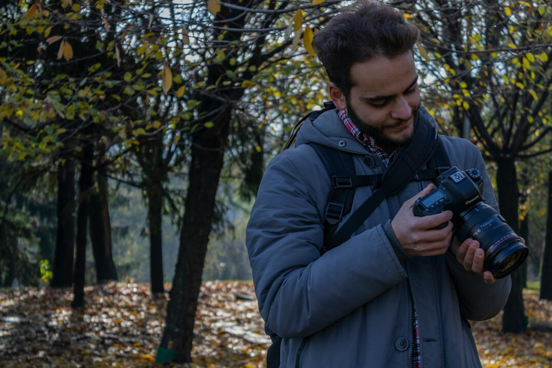 Polish documentary photographer smiling while holding a camera outdoors